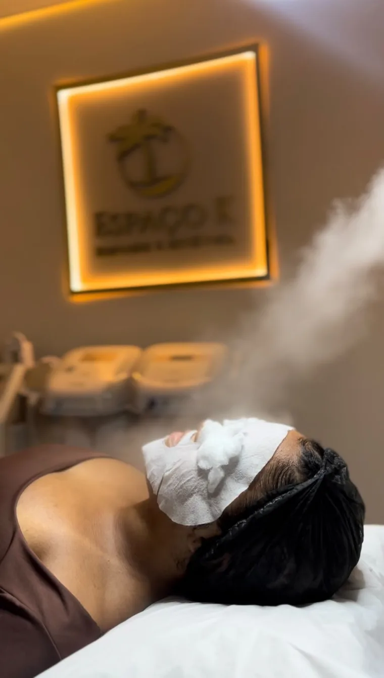 Cliente em cuidado de estética facial no Espaço K, com o letreiro dourado ao fundo