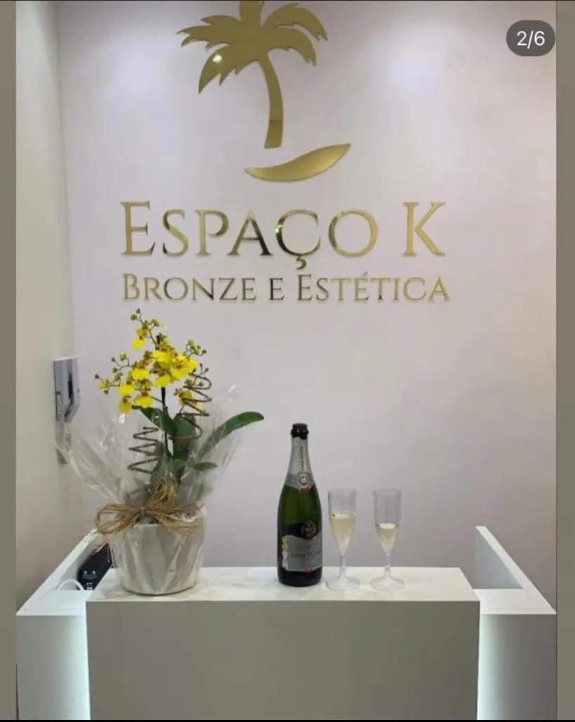Letreiro dourado do Espaço K com orquídea e taças de boas-vindas